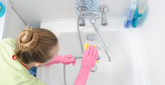 Entkalker: Frau putzt mit Entkalker die Armaturen im Bad